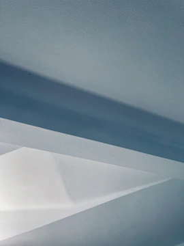 Abstract image featuring sleek geometric shapes in muted blue and sage green on an off-white background.