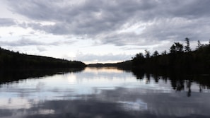 A quiet lakeside scene with reflections of a cloudy sky