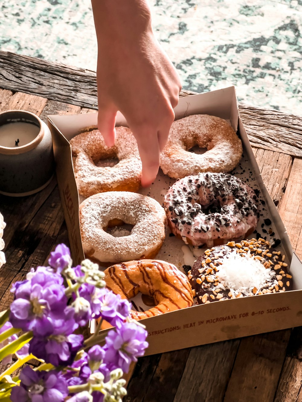 a person holding a box of donuts