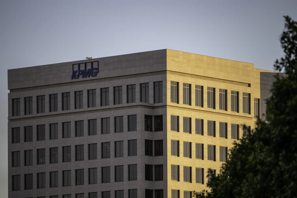 Large multi-story building with white exterior and beige accents features prominent KPMG logo prominently displayed