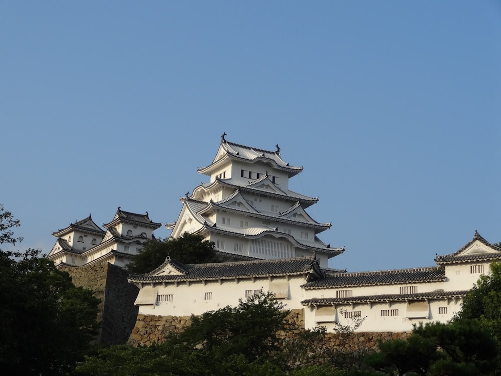 a large building with many rooftops with Himeji Castle in the background