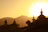 A serene sunrise over a sacred temple, casting golden light on peaceful pilgrims.