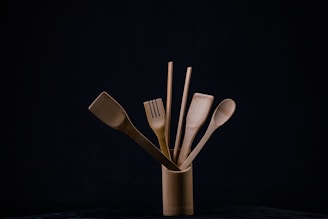 Bamboo utensil crock holding various wooden kitchen tools on a cozy countertop.