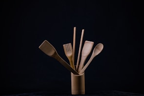 Bamboo utensil crock filled with wooden spoons and kitchen tools on a cozy kitchen counter.