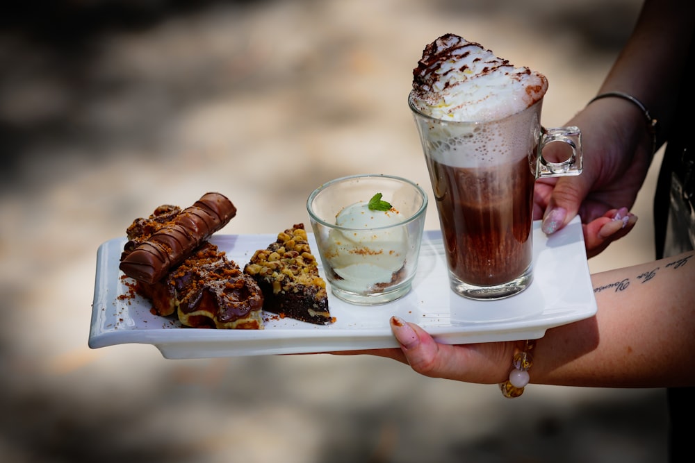 a person holding a glass of liquid and a plate of food