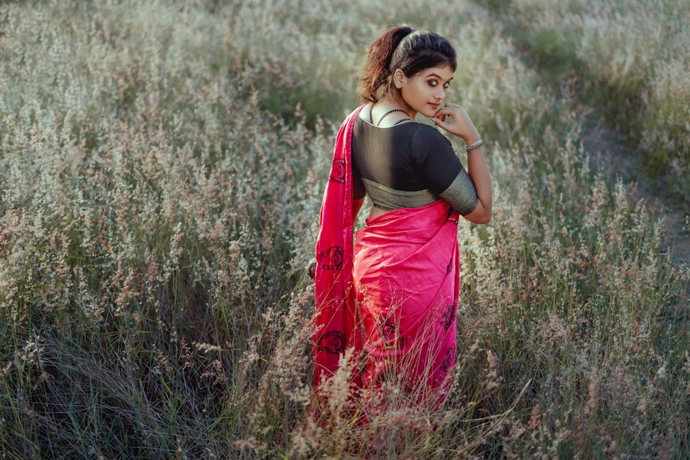 a person in a red dress standing in a field of tall grass