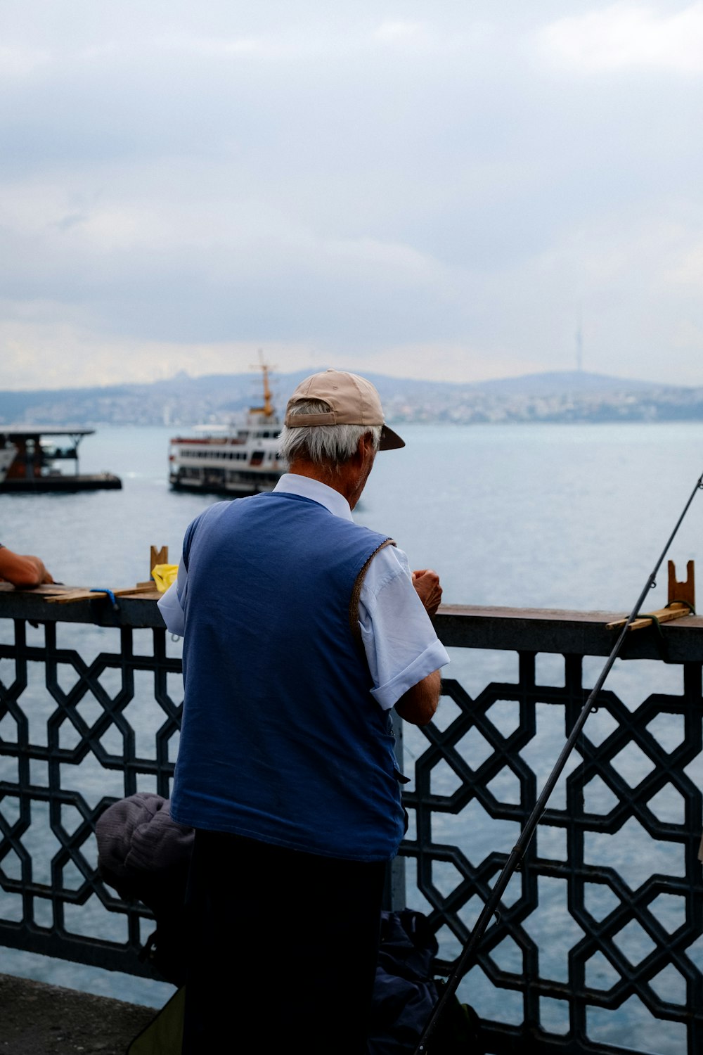 a person standing on a deck looking at a boat in the water