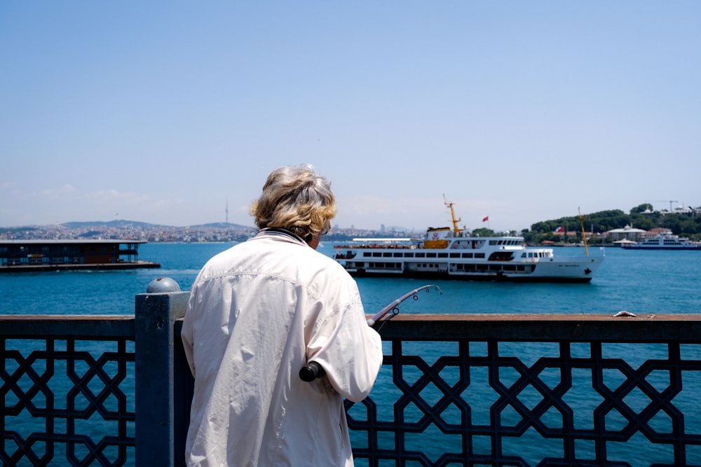 a person standing on a balcony looking at a boat on the water