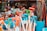 A vibrant collection of beach toys including shovels with colorful handles and nets in a bucket, displayed alongside a variety of plush toys inside a shop window.
