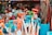 A vibrant collection of beach toys including shovels with colorful handles and nets in a bucket, displayed alongside a variety of plush toys inside a shop window.