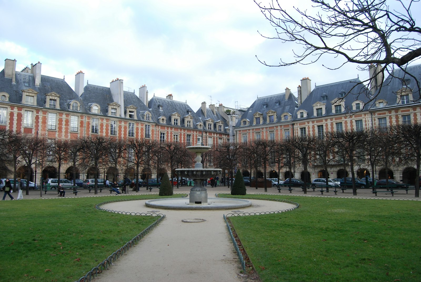 Red-brick arcaded houses and a fountain around the garden square of the Place des Vosges in the Marais