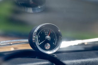Close-up of a black and white tachometer needle revving toward the redline, set against a transparent background.