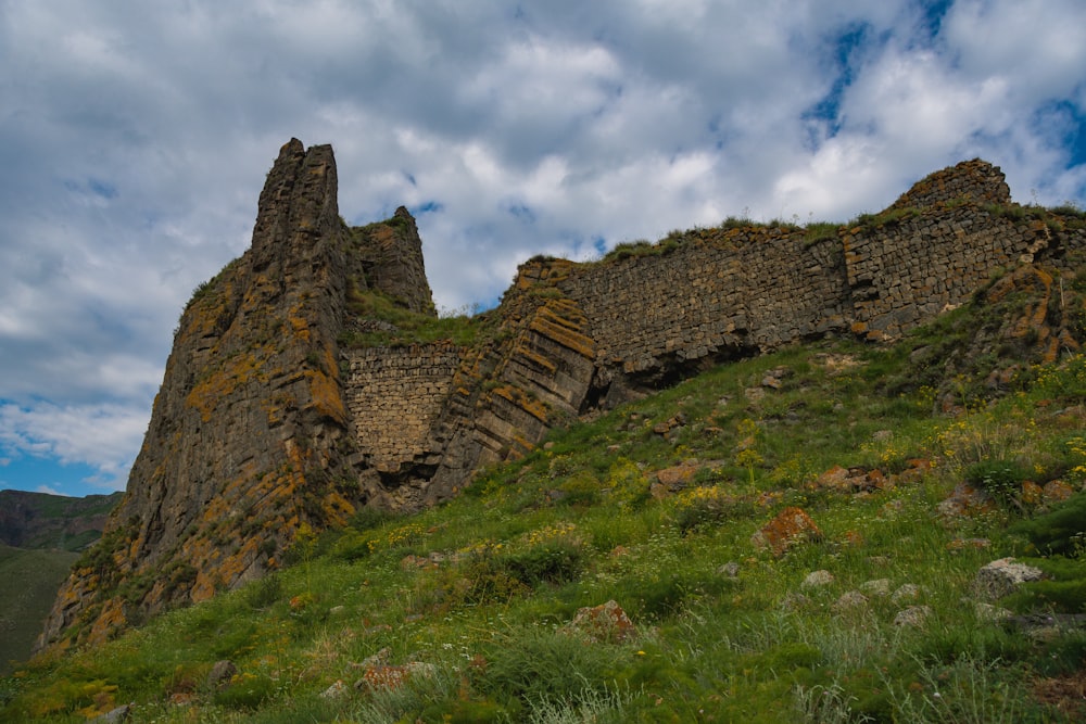 a rocky mountain with grass and blue sky with Montgomery Castle in the background