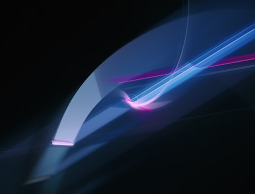 Abstract light painting features flowing, vibrant blue and pink lines against a dark background, creating a dynamic and futuristic appearance.