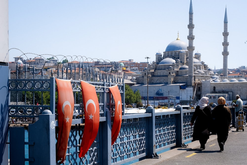 a group of people walking on a bridge with a building in the background