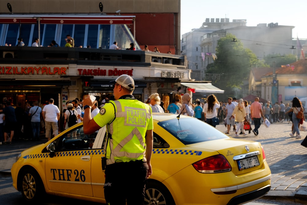 a person standing next to a yellow car with a crowd of people