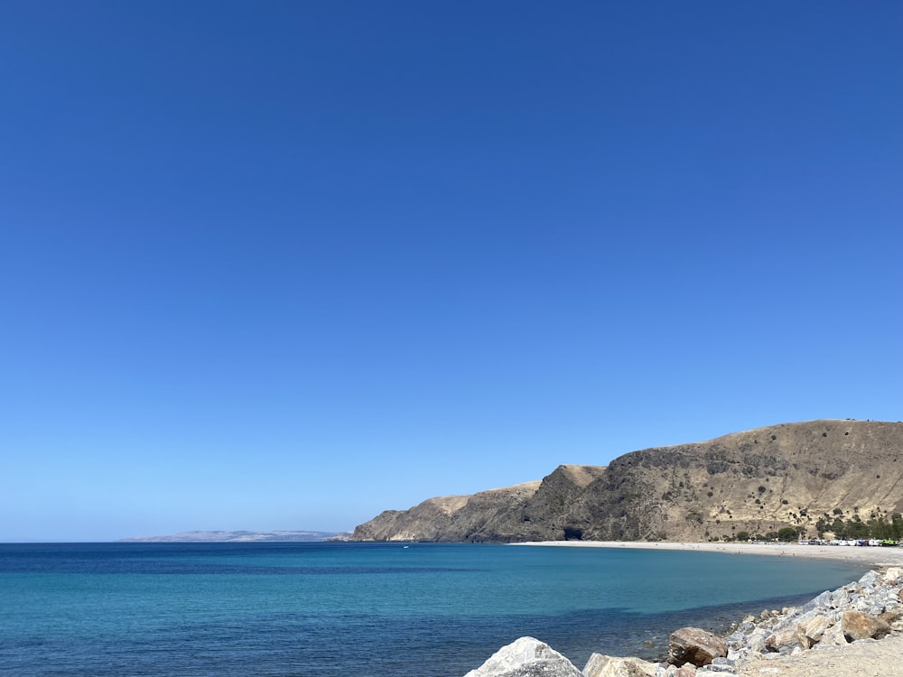 a rocky beach with a hill in the background