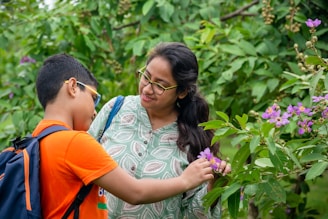 Young boy in orange shirt reaching out to purple flower, symbolizing the connection to nature 