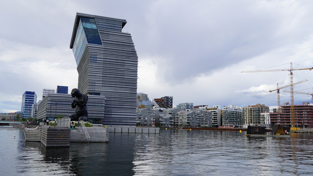 a body of water with buildings and cranes in the background