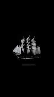 A detailed depiction of a sailboat with multiple large sails unfurled against a contrasting dark background, emphasizing the ship's structure and texture.