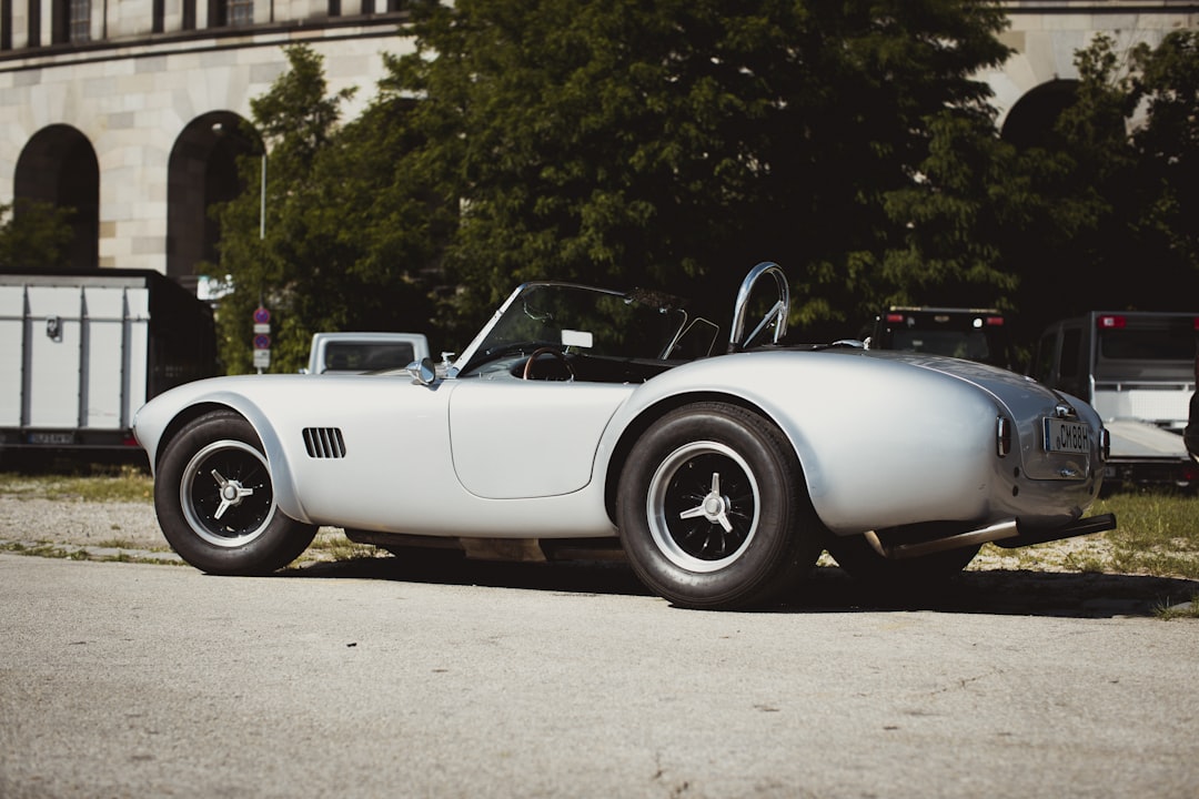 a car parked on the side of a road, Original british AC Cobra – Vintage oldtimer classic car