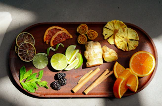 Fresh tropical fruits and spices arranged neatly on a wooden table under natural sunlight.