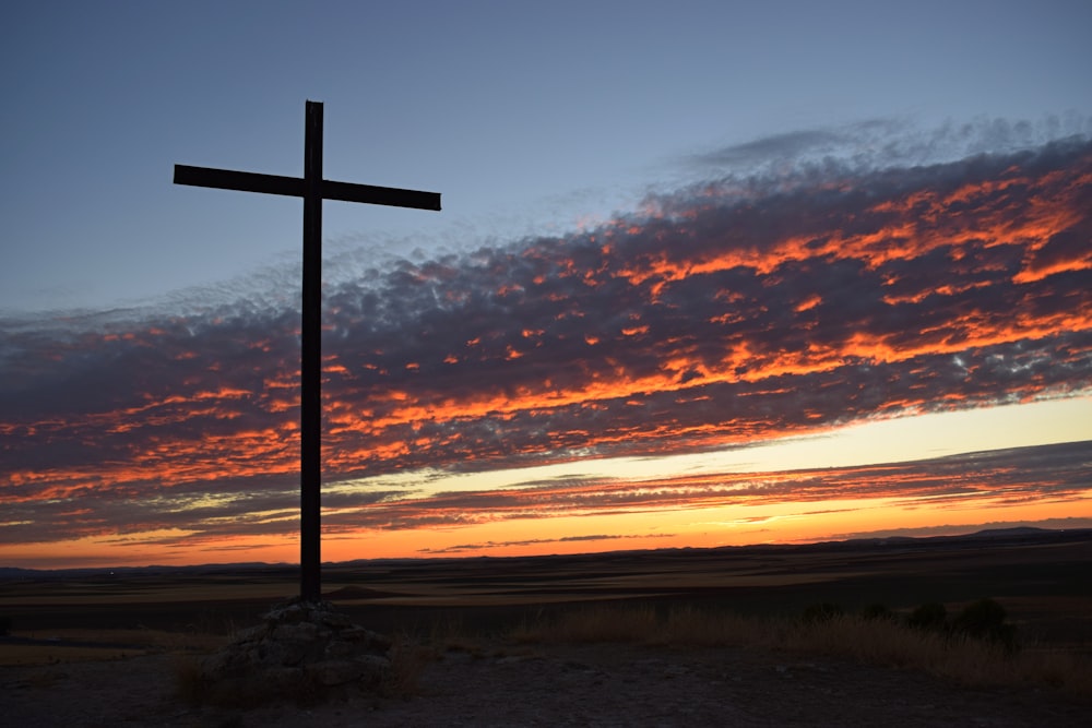 Una croce su una collina con un tramonto sullo sfondo