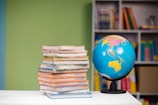 A stack of freshly printed books ready for worldwide distribution, with a globe in the background.