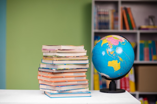 A stack of colorful books on a wooden shelf.