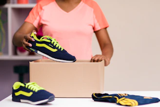 A customer happily packing a shoe box for return with a prepaid label.