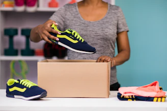 A sturdy army jungle shoe box being carefully packed for shipment against an olive green background.