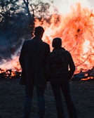 A couple enjoying a bonfire in the woods.