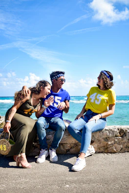 Group of friends laughing on a sunny Cape Town beach with clear blue waters