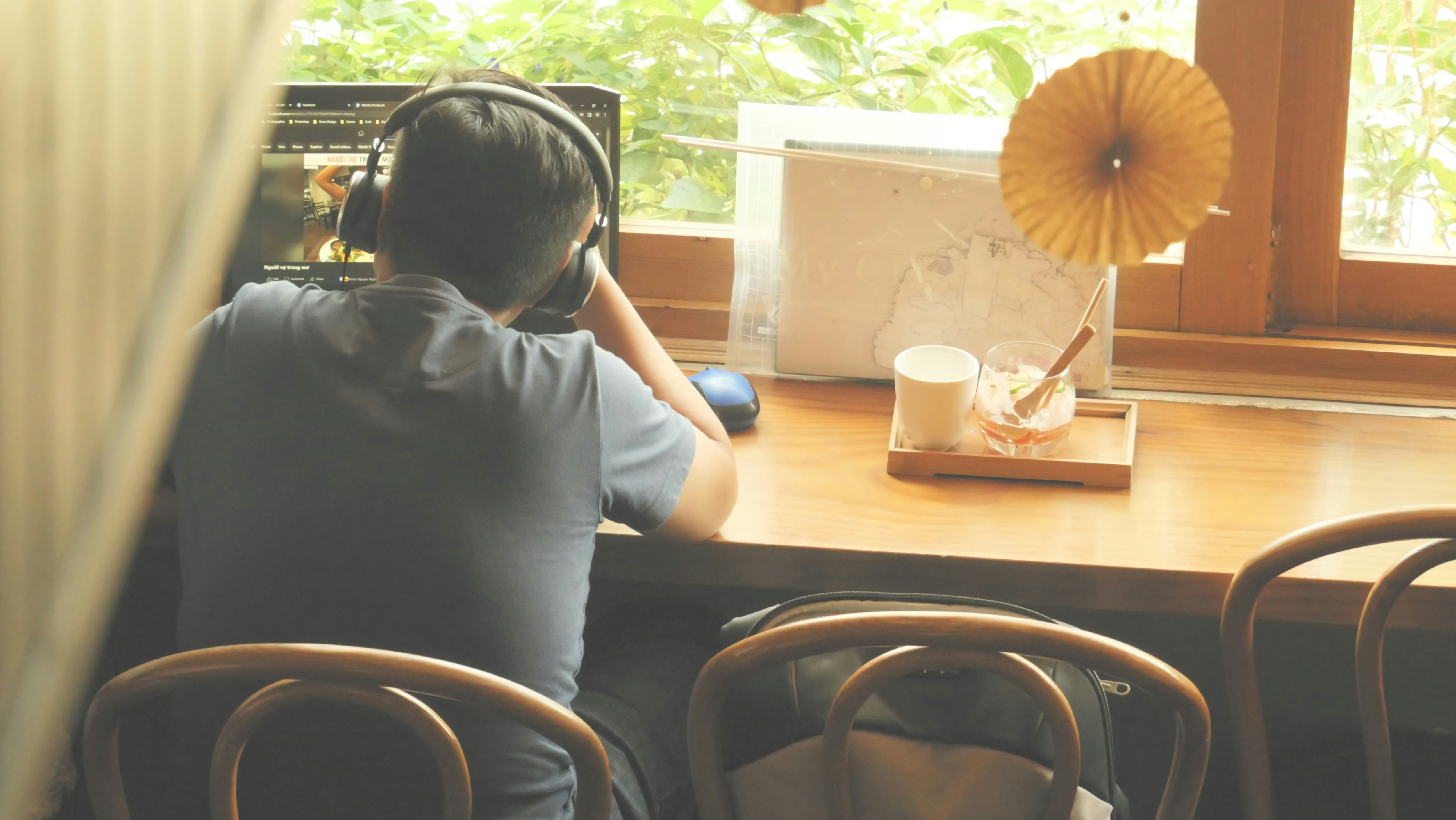 a person wearing headphones sitting at a table with a drink and food, 