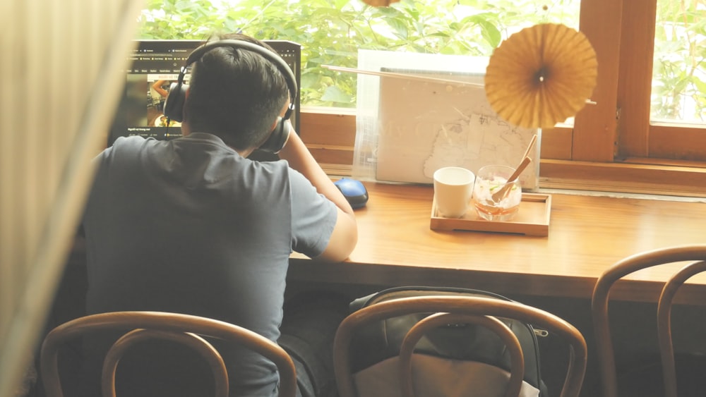 Una persona con auriculares sentada en una mesa con una bebida y comida