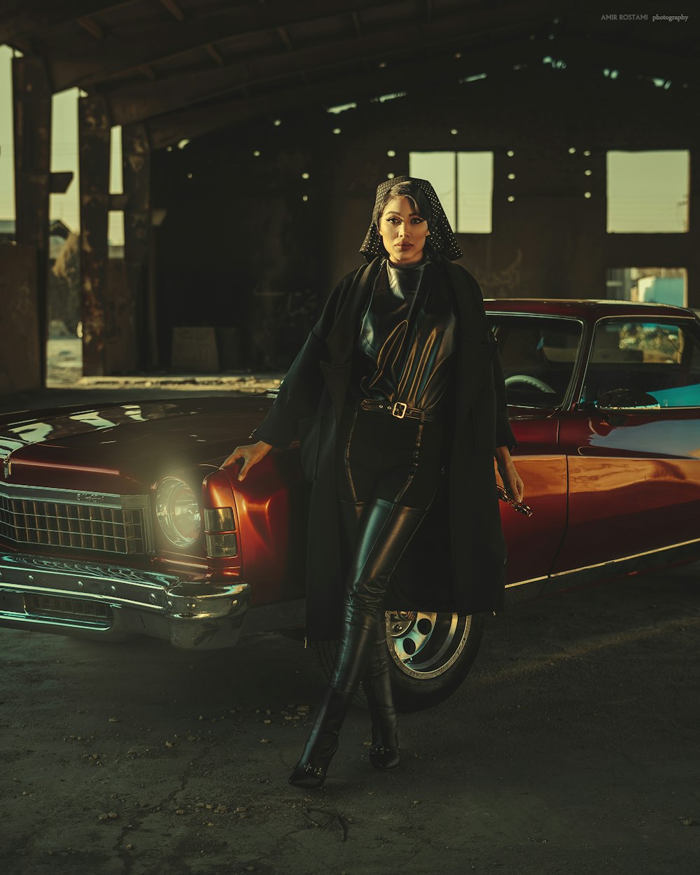 a man in a leather jacket standing next to a red car