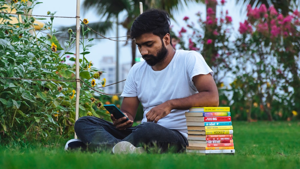 a man sitting on the grass looking at his phone