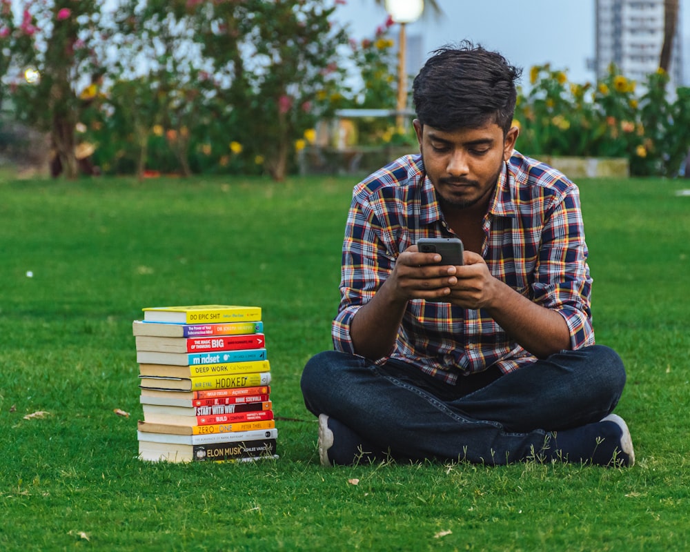 a man sitting on the grass looking at his phone