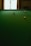 A green billiard table with three balls positioned on it, including a red ball in the center and two yellow balls at different angles. There is a window in the background that casts natural light onto the scene.