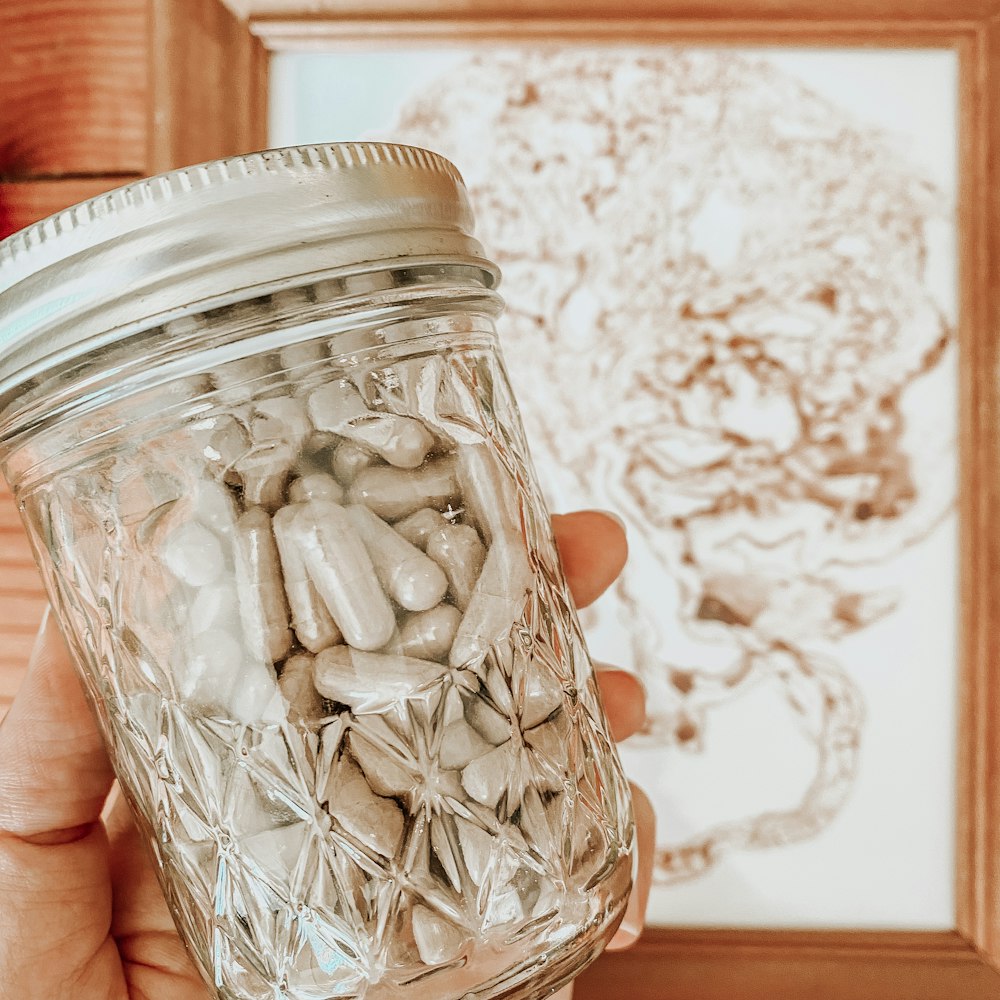 a hand holding a jar of white substance