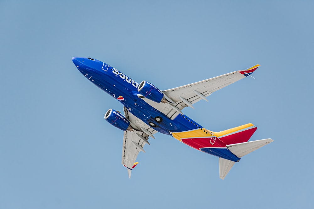 a blue and white airplane flying in the sky