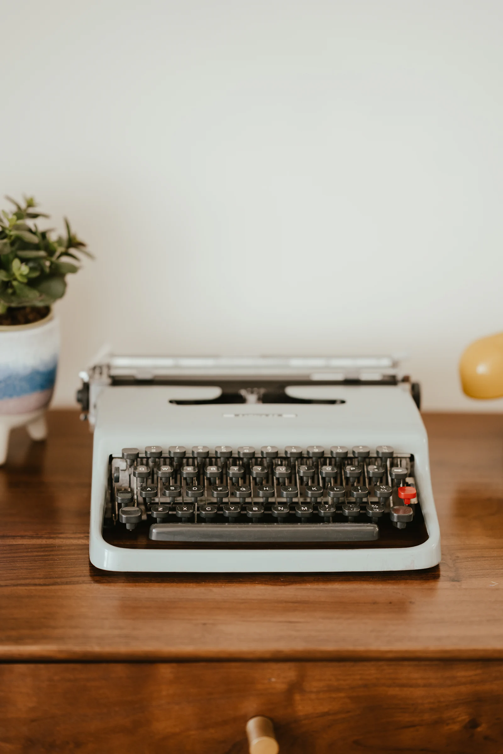 A black and silver typewriter standing on a wooden table.