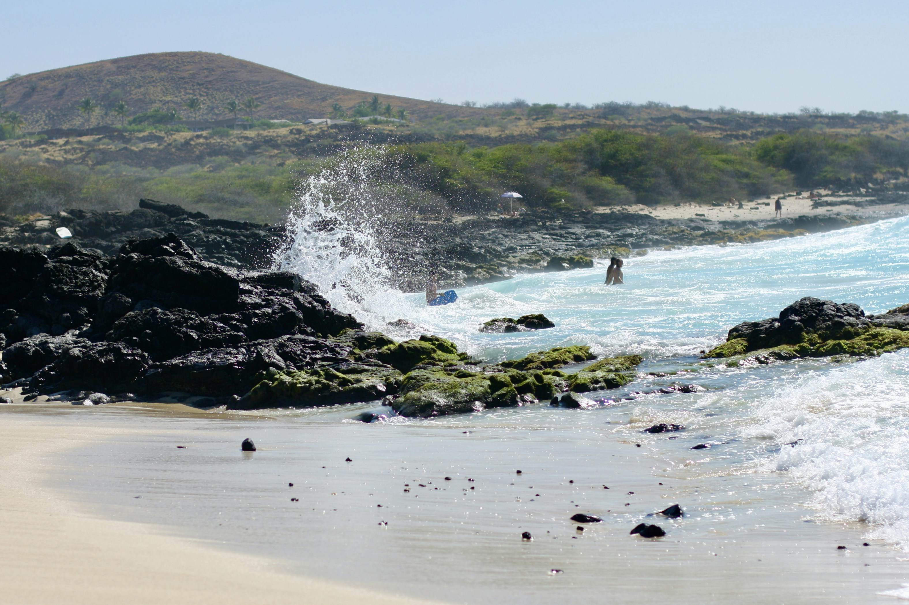 a beach with a large body of water and a large wave crashing