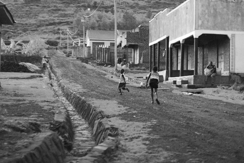 a couple of kids playing in a dirt road