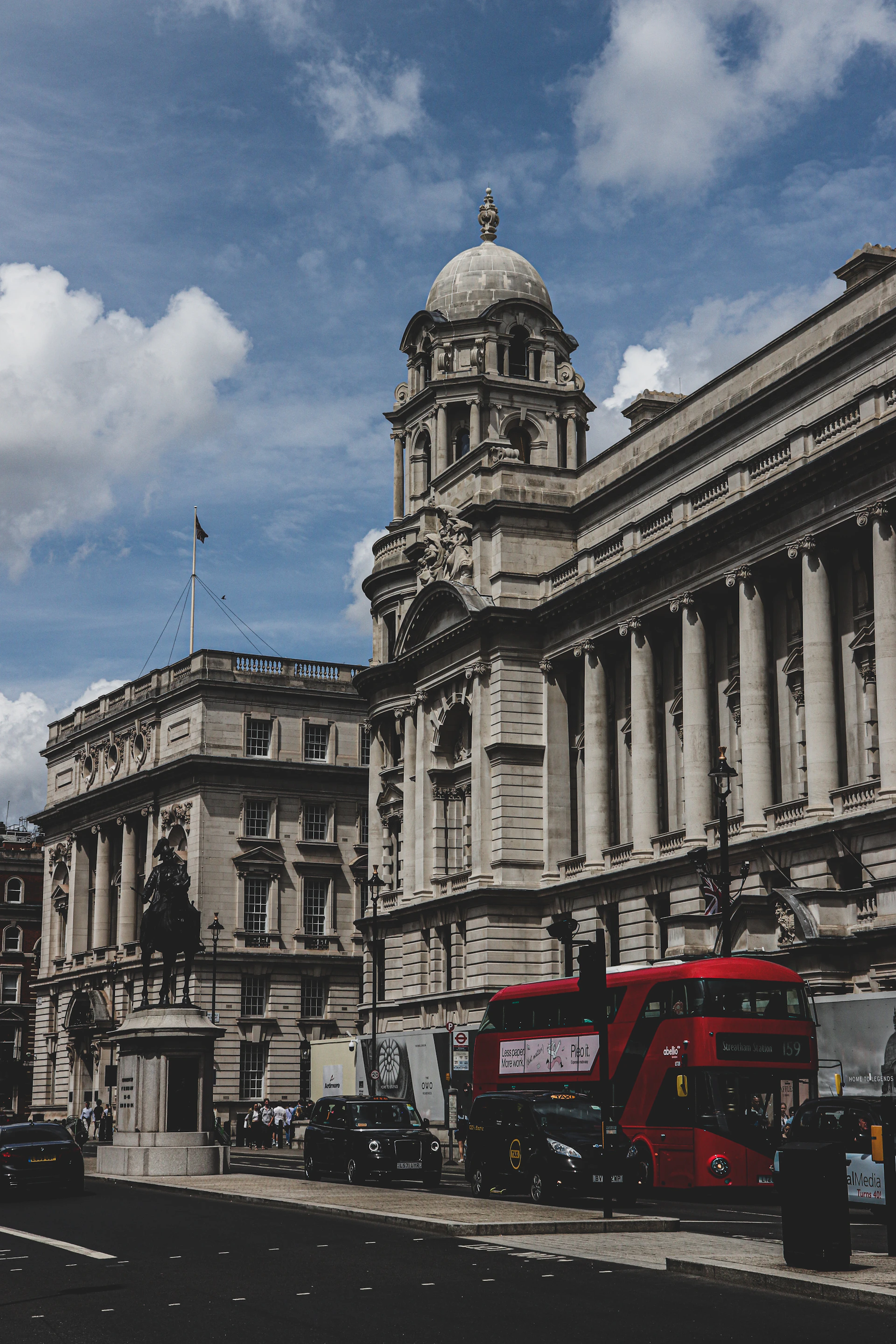 A striking image of Buckingham Palace framed by a bright blue sky, with a black cab parked nearby, ready to take guests on a historic tour.