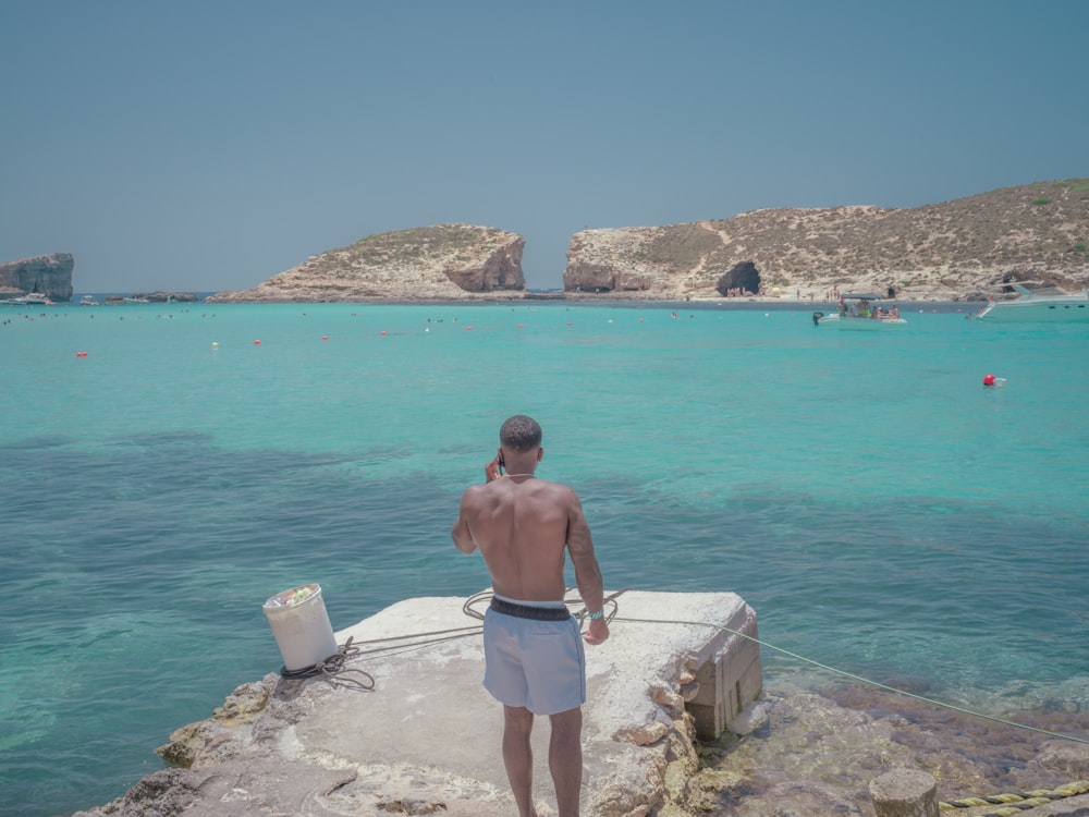 a person standing on a rock by the water