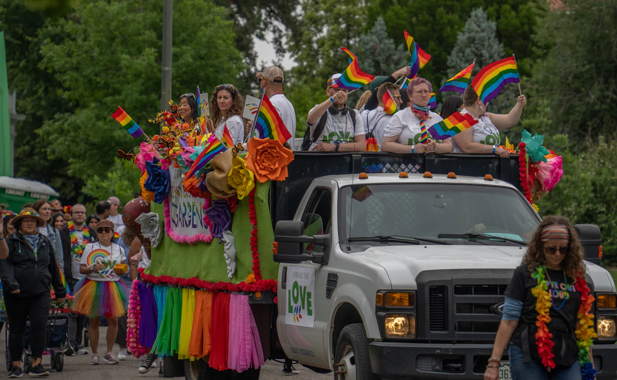 Denver Pride parade float with rainbow flags and community members celebrating on Colfax Avenue
