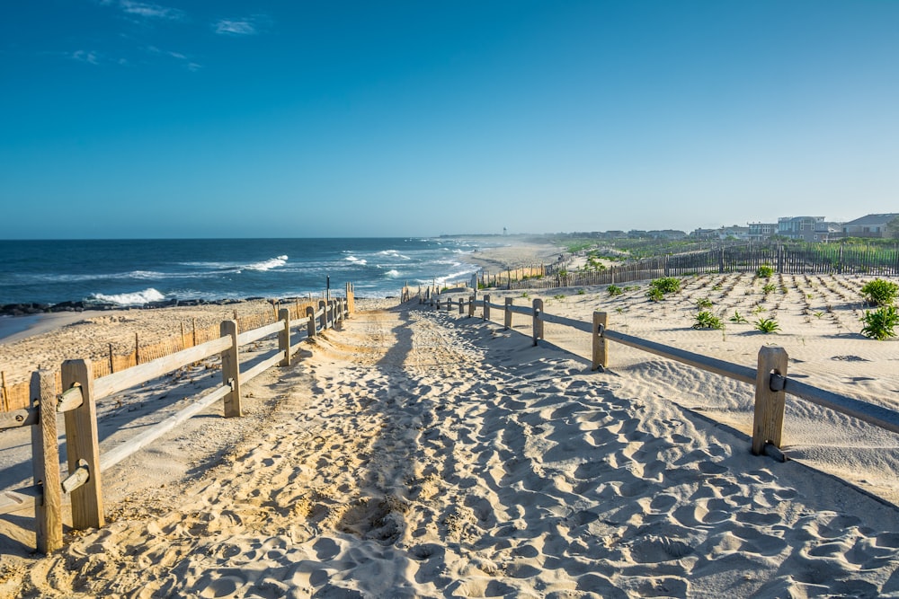 a sandy beach with a wooden fence