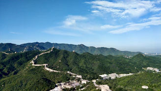 A panoramic view of the Great Wall winding over rugged mountains under a clear blue sky.