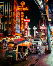 a street with neon signs and scooters